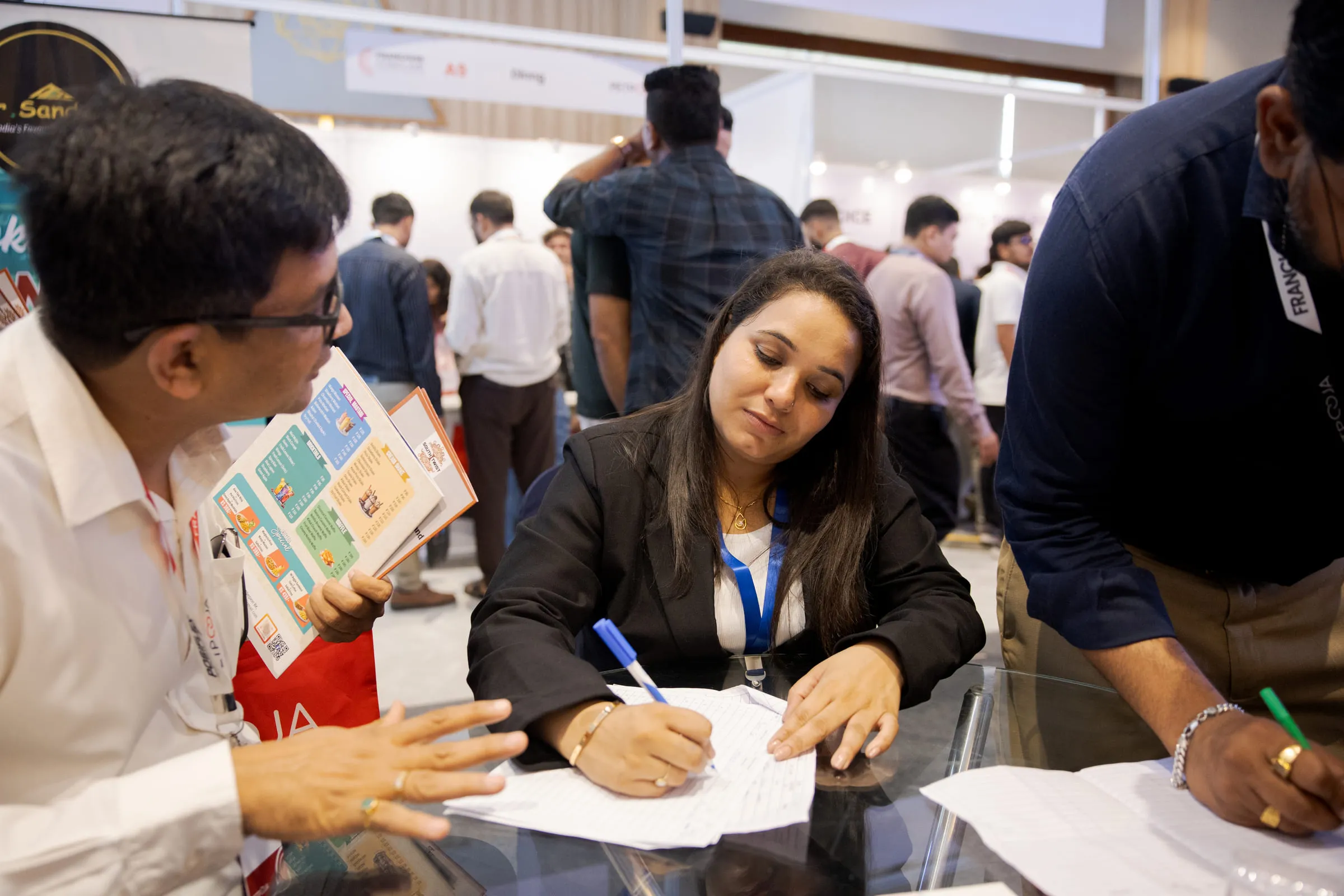 A visitor filling in franchise paperwork at a brand's stall