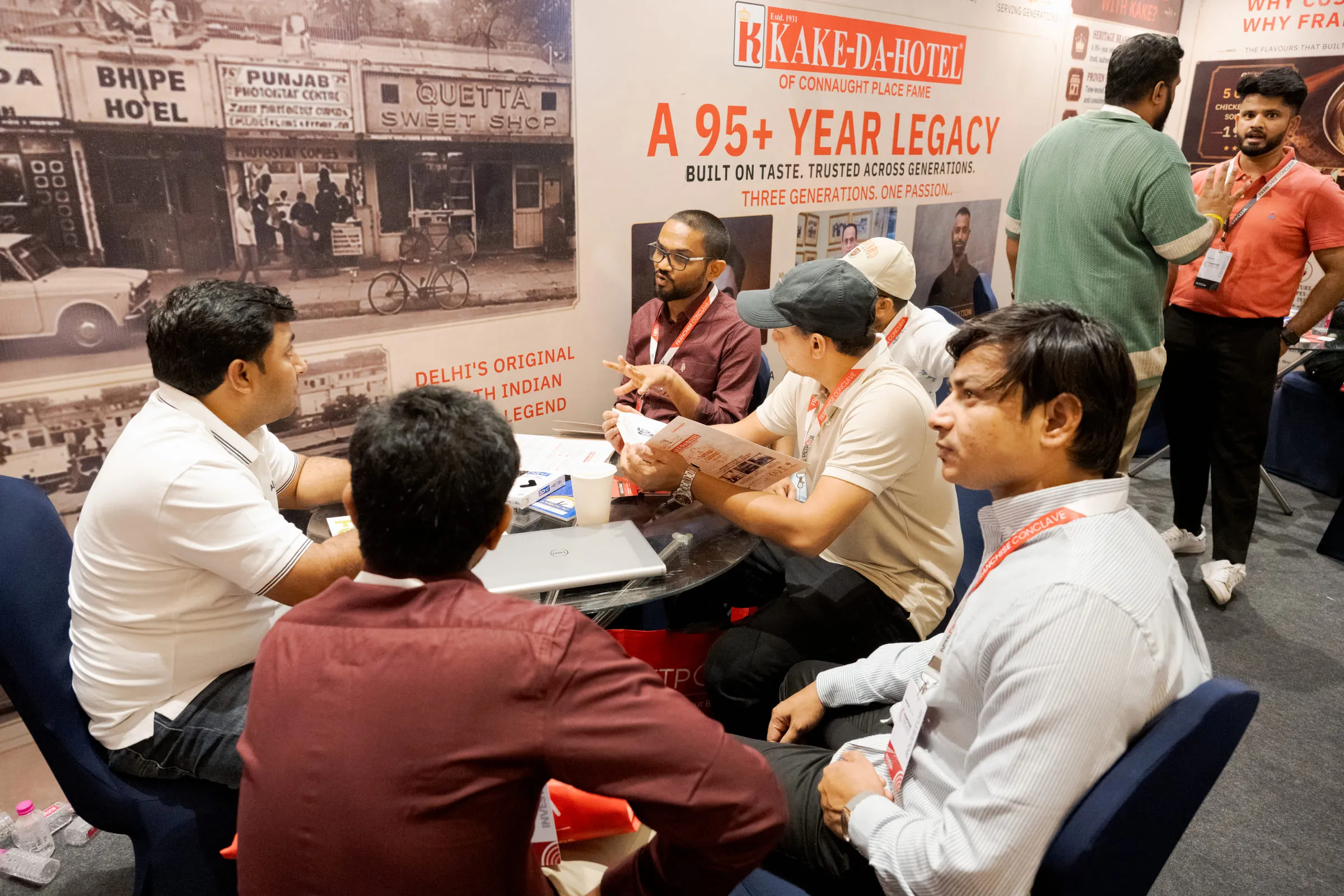 A group meeting at the Kake-Da-Hotel stall beneath its 95+ year legacy banner